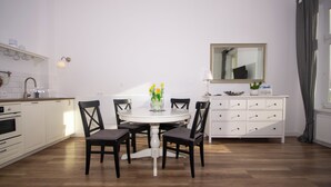 A modern kitchen with white cabinetry, a round dining table with chairs, a white dresser, and a mirror above the dresser. - InPoint Boutique Apartments near MainSQ (Kraków)