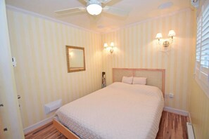 Ein Schlafzimmer mit einem Bett, einem Deckenventilator, einem Spiegel und Wandleuchten.