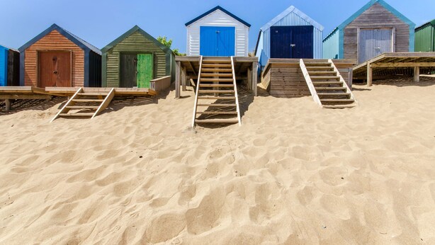 Una hilera de cabañas de playa con escaleras de madera que conducen a cada una.