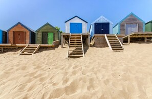 Una fila di cabine sulla spiaggia, con scale in legno che conducono all'ingresso di ciascuna.