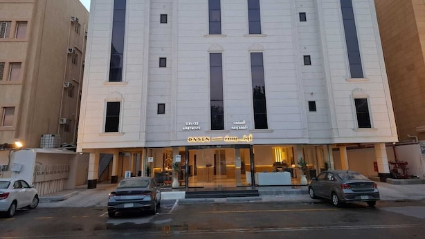A multi-story building with a central entrance, large windows, and a sign indicating it is a serviced apartment complex. - Onsen Hotel Al Shati (Dammam)