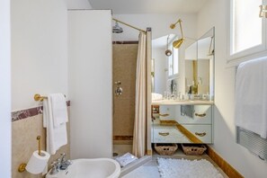 Une salle de bain moderne équipée d’une baignoire, d’une douche, d’un meuble-lavabo avec miroir et de toilettes.