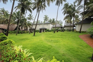 A well-maintained lawn with a few palm trees and a building with a tiled roof.