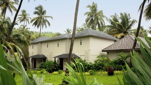 A building with a tiled roof, surrounded by lush greenery and palm trees. - The Earth-Maison Ocean Beach Resort (Ashvem)