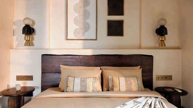 A hotel room with a large bed, two bedside tables, a headboard, and wall-mounted artwork. - The Earth-Maison Ocean Beach Resort (Ashvem)