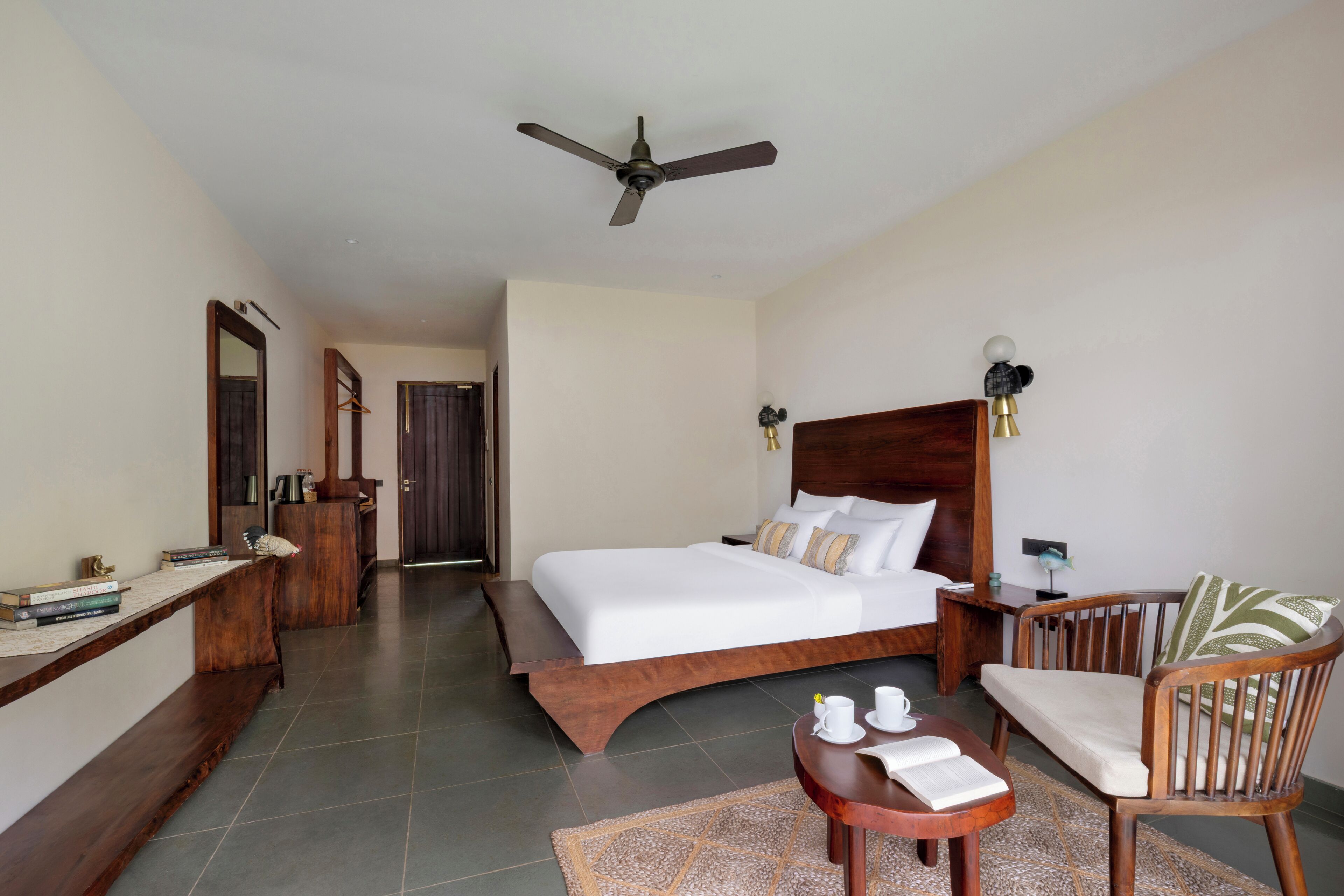 A hotel room with a bed, a desk, a chair, a ceiling fan, and a nightstand.