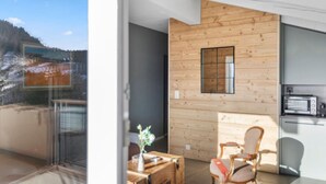 Ein modernes Interieur mit einer Holzwand, einer kleinen Küchenzeile und Blick auf eine verschneite Landschaft.