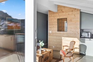 Ein modernes Interieur mit einer Holzwand, einer kleinen Küchenzeile und Blick auf eine verschneite Landschaft.