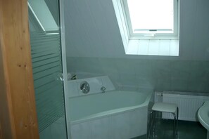 Et moderne badeværelse med ovenlys, badekar, toilet og håndvask.