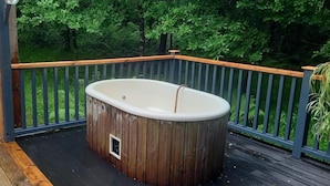 A hot tub on a wooden deck with a view of a forest. - Sheperd's Hut, Sleeps 2 With Hot Tub and Garden (Glengarriff)