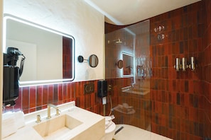 A bathroom with a large mirror, a sink with two faucets, a toilet, and a shower area with a glass door. - YU Townhouse (Bodrum)