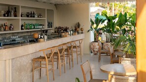 A bar area with a ruffled ceiling, wicker furniture, and a view of a tropical garden.