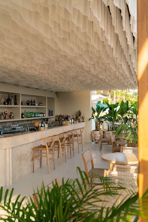 A bar area with a ruffled ceiling, wicker furniture, and a view of a tropical garden. - YU Townhouse (Bodrum)