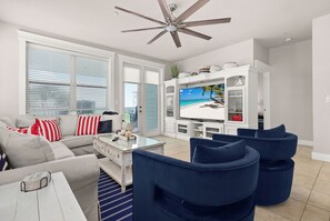 Ein Wohnzimmer mit Ecksofa, Couchtisch, Fernseher und Deckenventilator.