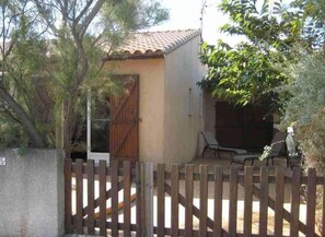 A small building with a tiled roof, a wooden gate, and a fenced patio area with outdoor furniture. - LA FRANQUI 6 people, Pets (LA FRANQUI)