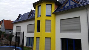 Eine Reihe von Häusern mit unterschiedlichen Architekturstilen, darunter ein gelbes Gebäude mit blauem Fensterrahmen und ein graues Gebäude mit rotem Dach.