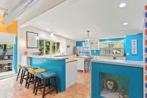 Une cuisine moderne dotée d’un îlot central, de tabourets de bar et offrant une vue sur l’extérieur.