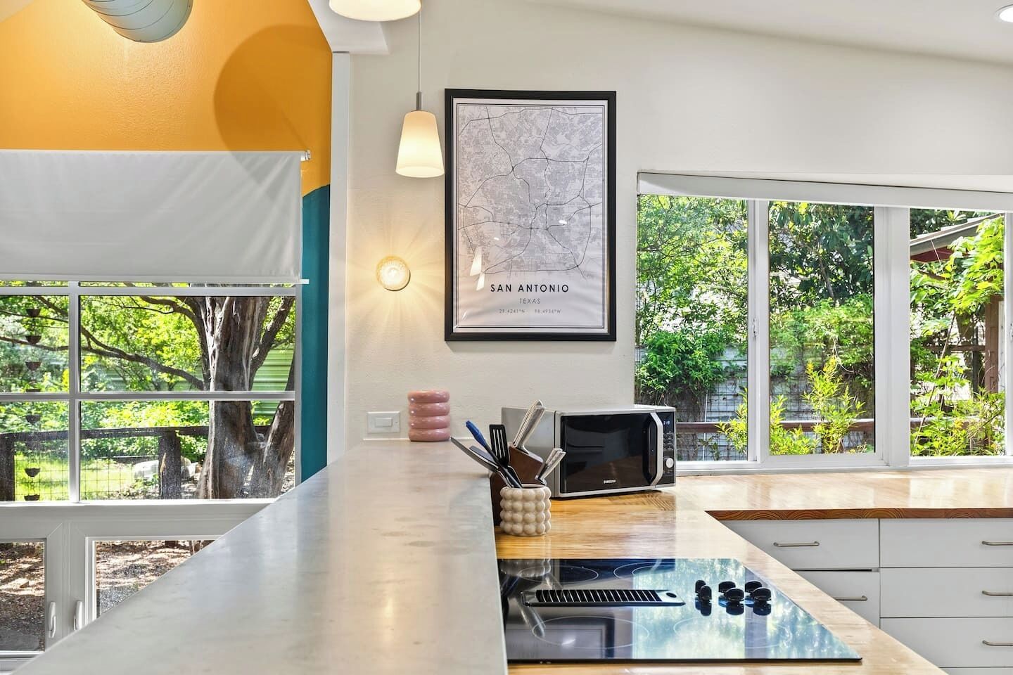 Una cocina con una isla grande, un microondas y un tostador. Hay un mapa enmarcado en la pared y una ventana con vistas a zonas verdes.