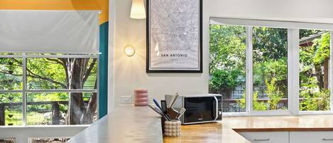 Una cocina con una isla grande, un microondas y un tostador. Hay un mapa enmarcado en la pared y una ventana con vistas a zonas verdes.