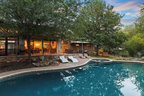 Une piscine avec des chaises longues, un espace patio et un bâtiment doté de grandes fenêtres.