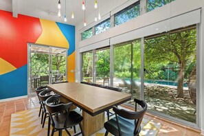 Une salle de conférence dotée d’une longue table, de chaises et de grandes fenêtres donnant sur un jardin.