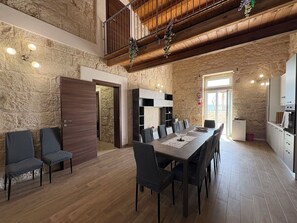 A spacious dining area with a high ceiling and exposed wooden beams, a stone wall, and a view of the outdoors. - Stunning private villa with WIFI, private pool, A/C, TV, patio, pets allowed and panoramic view (Santa Croce Camerina)