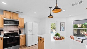 Une cuisine moderne avec des meubles en bois, des appareils électroménagers en acier inoxydable et un îlot central.
