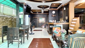 Un interior moderno con techo de madera, un mostrador de recepción, una escalera y zonas de estar.