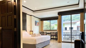 Una habitación de hotel con cama, escritorio, silla, ventana y balcón.