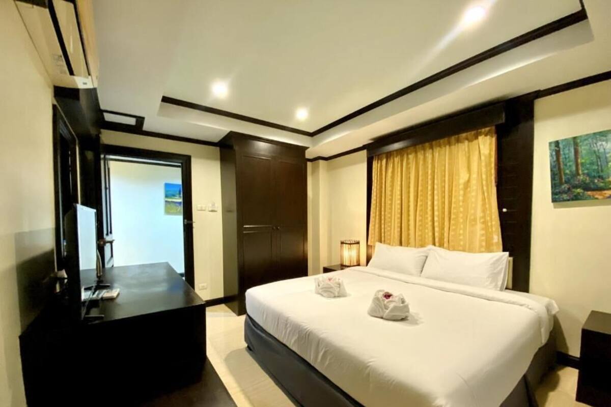 A hotel room with a large bed, a desk, and a painting on the wall.