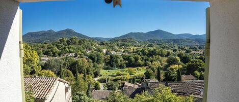 Vista desde una ventana sobre un pueblo con edificios tradicionales y montañas al fondo.