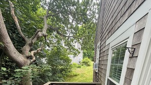 A wooden deck with two gray sofas and a small table, surrounded by a wooden railing. - Charming 2 bedroom cottage by the pond in Eastham, Cape Cod (Eastham)