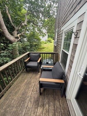 En træterrasse med to grå sofaer og et lille bord, omgivet af et trægelænder.