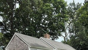 A two-story house with a gravel driveway and a wooden deck. - Charming 2 bedroom cottage by the pond in Eastham, Cape Cod (Eastham)