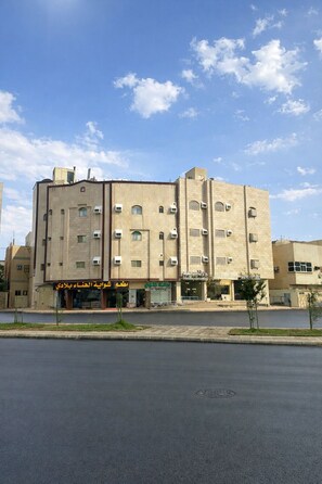 Un edificio de varios pisos con fachada plana, unidades de aire acondicionado y escaparates con letreros.