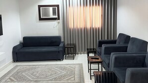 Una sala de estar moderna con un sofá oscuro, una mesa de centro y un televisor montado en la pared.