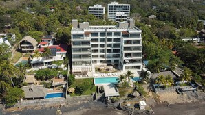 Un hotel de varios pisos con piscina, rodeado de exuberante vegetación y palmeras.