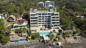 Ein mehrstöckiges Hotel mit Pool, umgeben von üppiger Vegetation und Palmen.