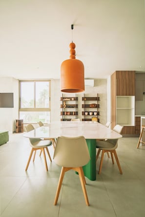 Un comedor moderno con una mesa grande, sillas y una lámpara colgante naranja original.
