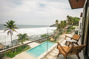 Un balcón con piscina, sillas y vistas al océano.