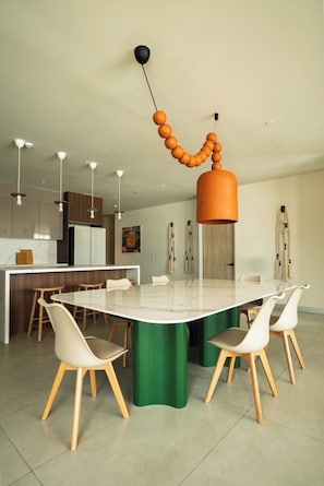Une cuisine moderne dotée d’un îlot central, de luminaires suspendus et d’un coin repas avec des chaises et une table.