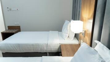 Una habitación de hotel con una cama individual, una mesita de noche y una lámpara fijada a la pared.