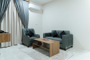 Uma sala de estar moderna com dois sofás cinzentos, uma mesa de centro de madeira e um tapete cinza.