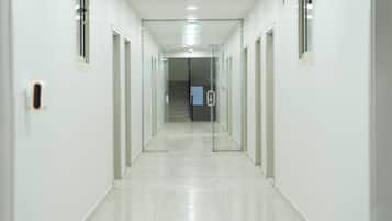 Un pasillo largo y estrecho con puertas de cristal a ambos lados, que conduce a una escalera.