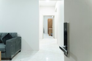 Um corredor com um sofá, uma televisão e uma porta de madeira no final.
