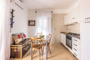 A compact kitchen with a dining table, chairs, a stove, and a chest of drawers. - Casa Vacanza Famiglia Schiavone  (Matera)
