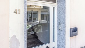 En byggnadsentré med en glasdörr, en bil parkerad inuti och en brevlåda med texten ”PUBLICA”.