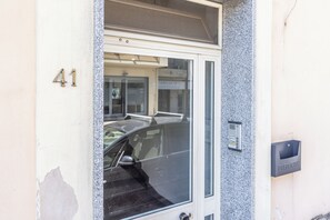 A building entrance with a glass door, a car parked inside, and a mailbox labeled 'PUBLICA'. - Casa Vacanza Famiglia Schiavone  (Matera)