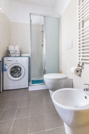 A bathroom with a washing machine, toilet, and sink. - Casa Vacanza Famiglia Schiavone  (Matera)