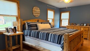 Una cama de madera con cabecera, mesitas de noche y un aparador con fotografías enmarcadas.